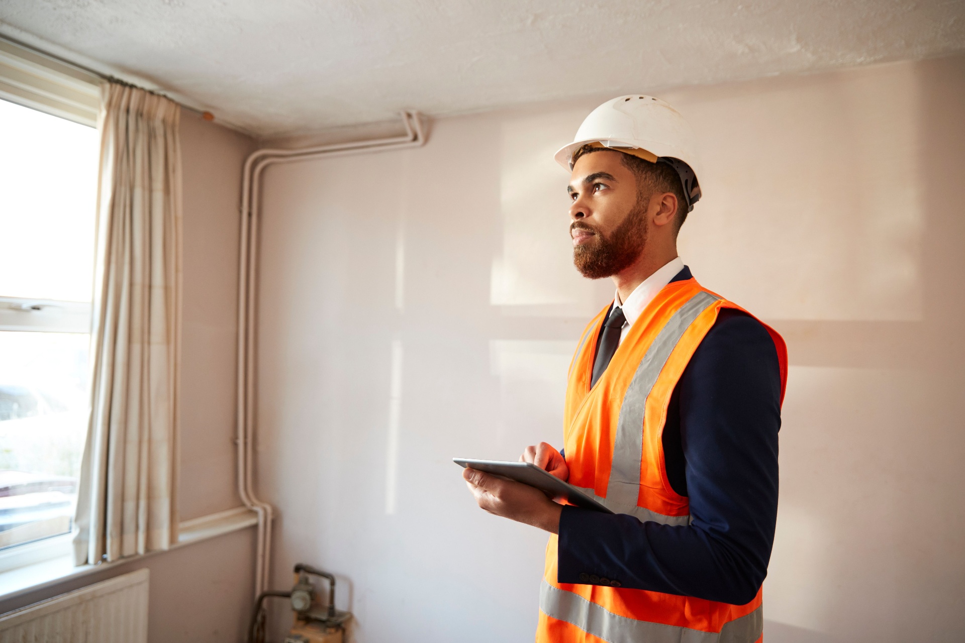 Professional surveyor with hard hat and high-vis vest conducting moisture meter survey